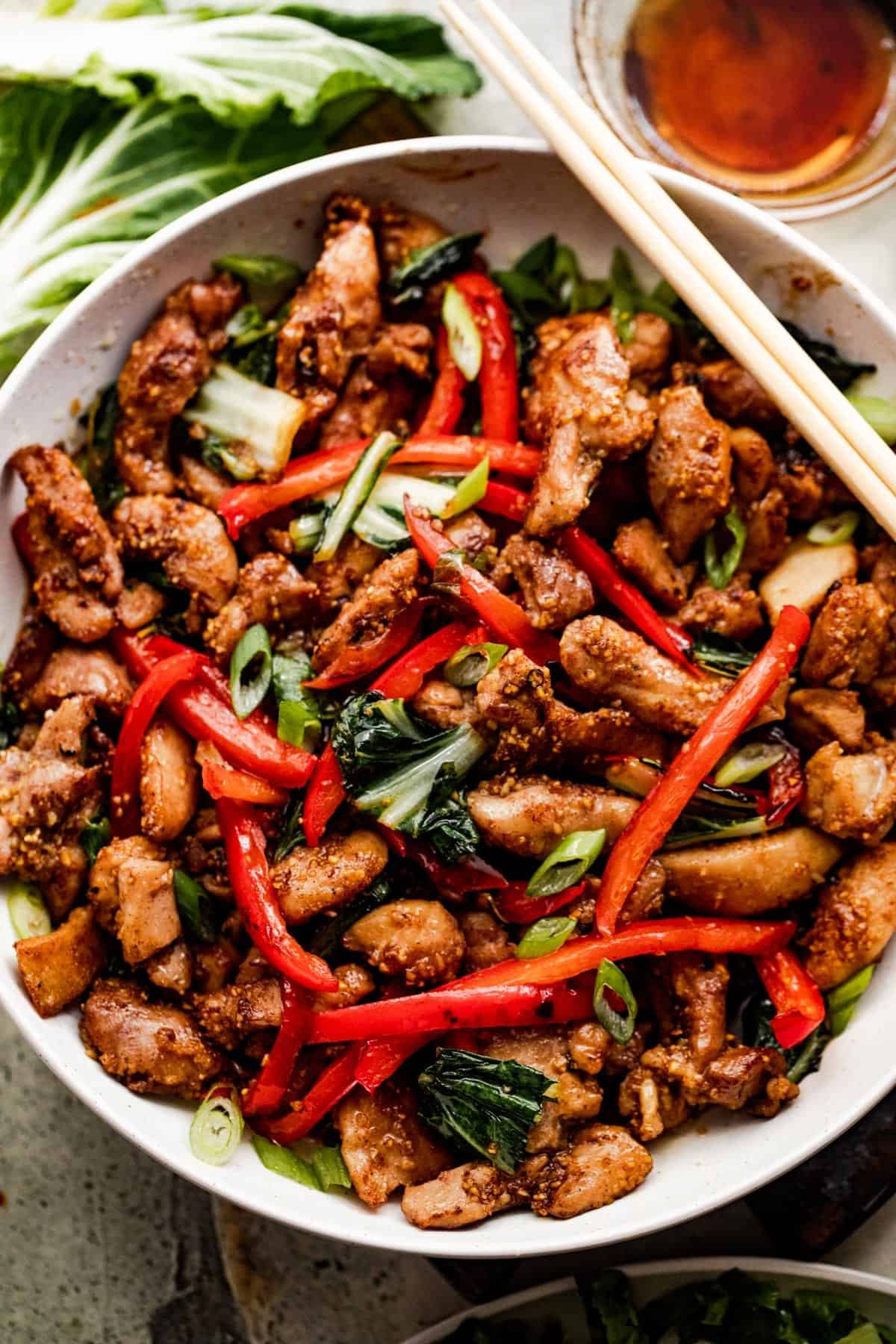 overhead shot of salt and pepper chicken in a white bowl with two chopsticks resting on top of the bowl.