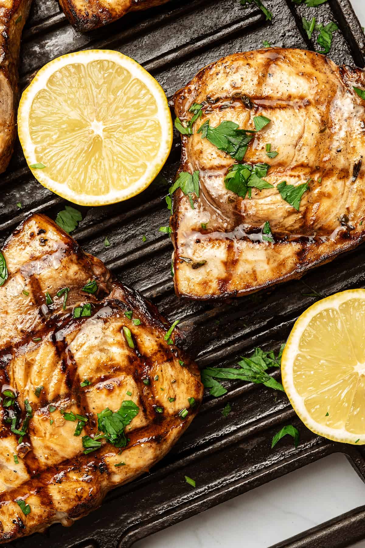 Cooked swordfish steaks on a grill with lemon slices