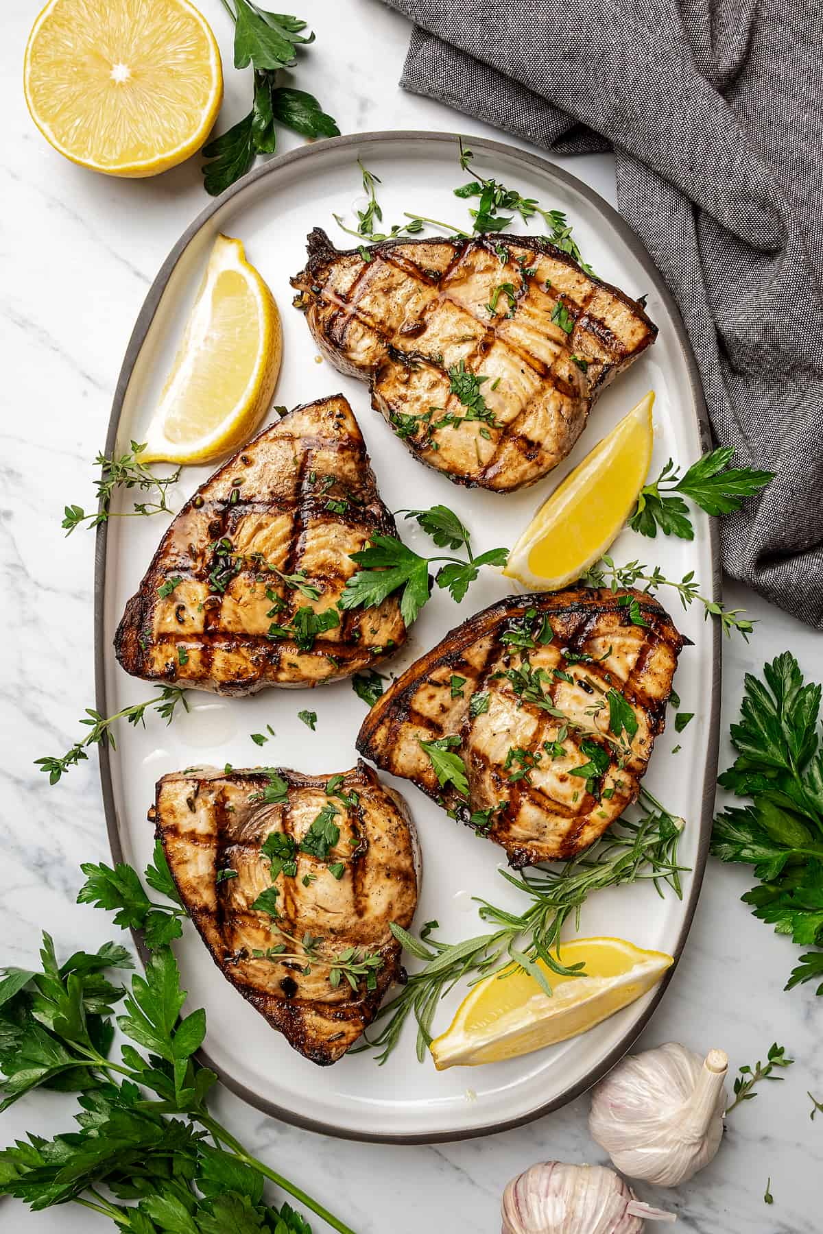 4 grilled swordfish steaks on a serving platter with lemon wedges