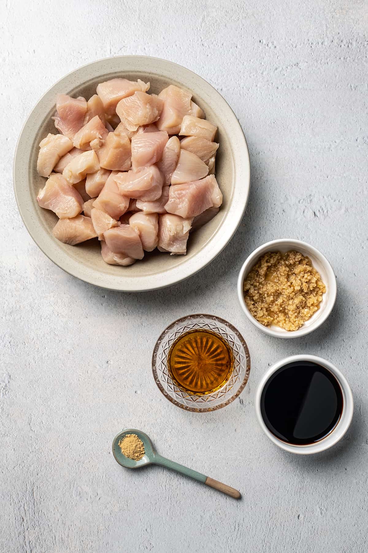White bowl with raw chicken, sauce an other hibachi chicken ingredients