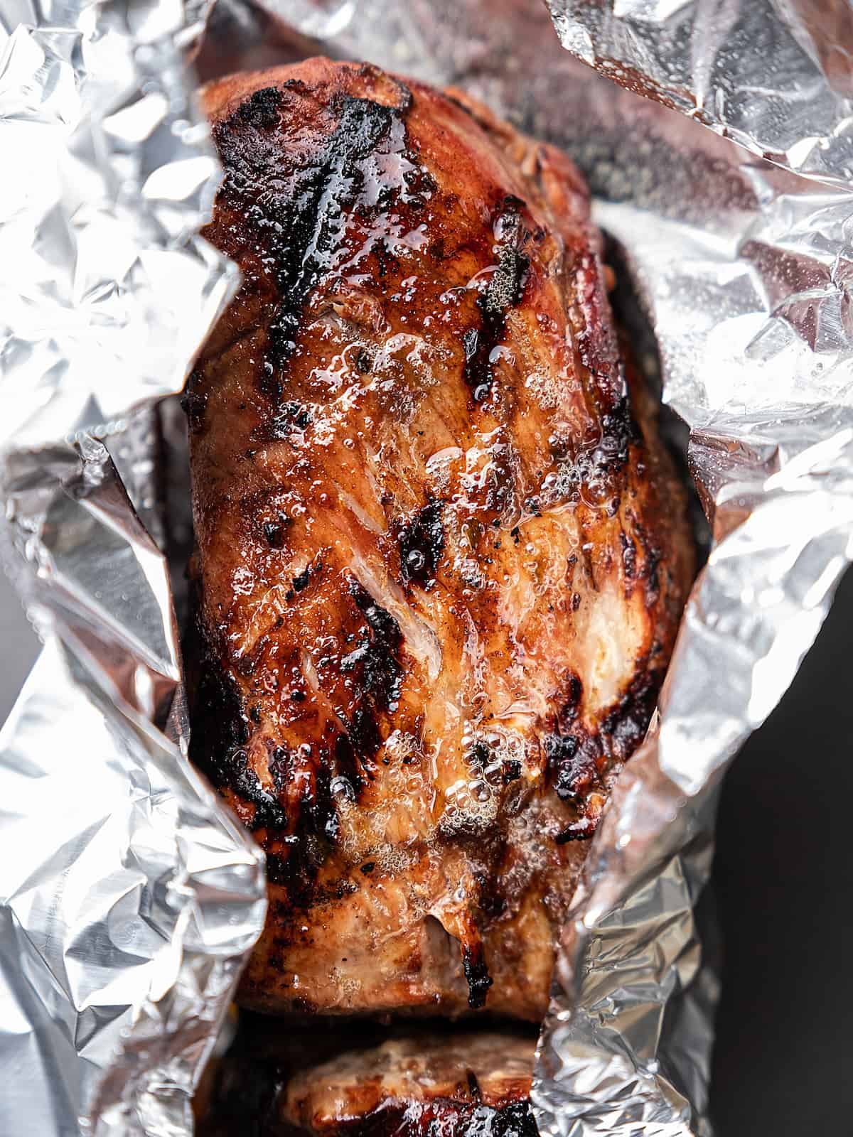 A freshly grilled pork tenderloin on top of a piece of aluminum foil