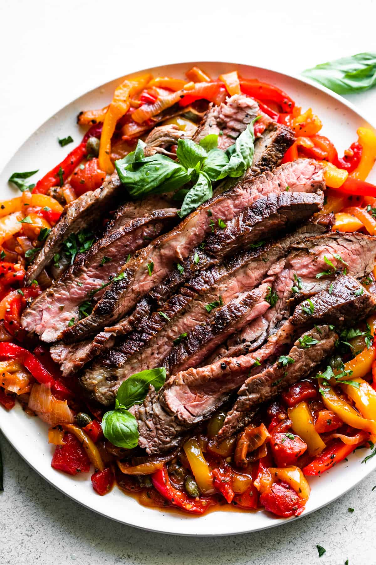 slices of grilled flank steak served over a bed of peperonata.