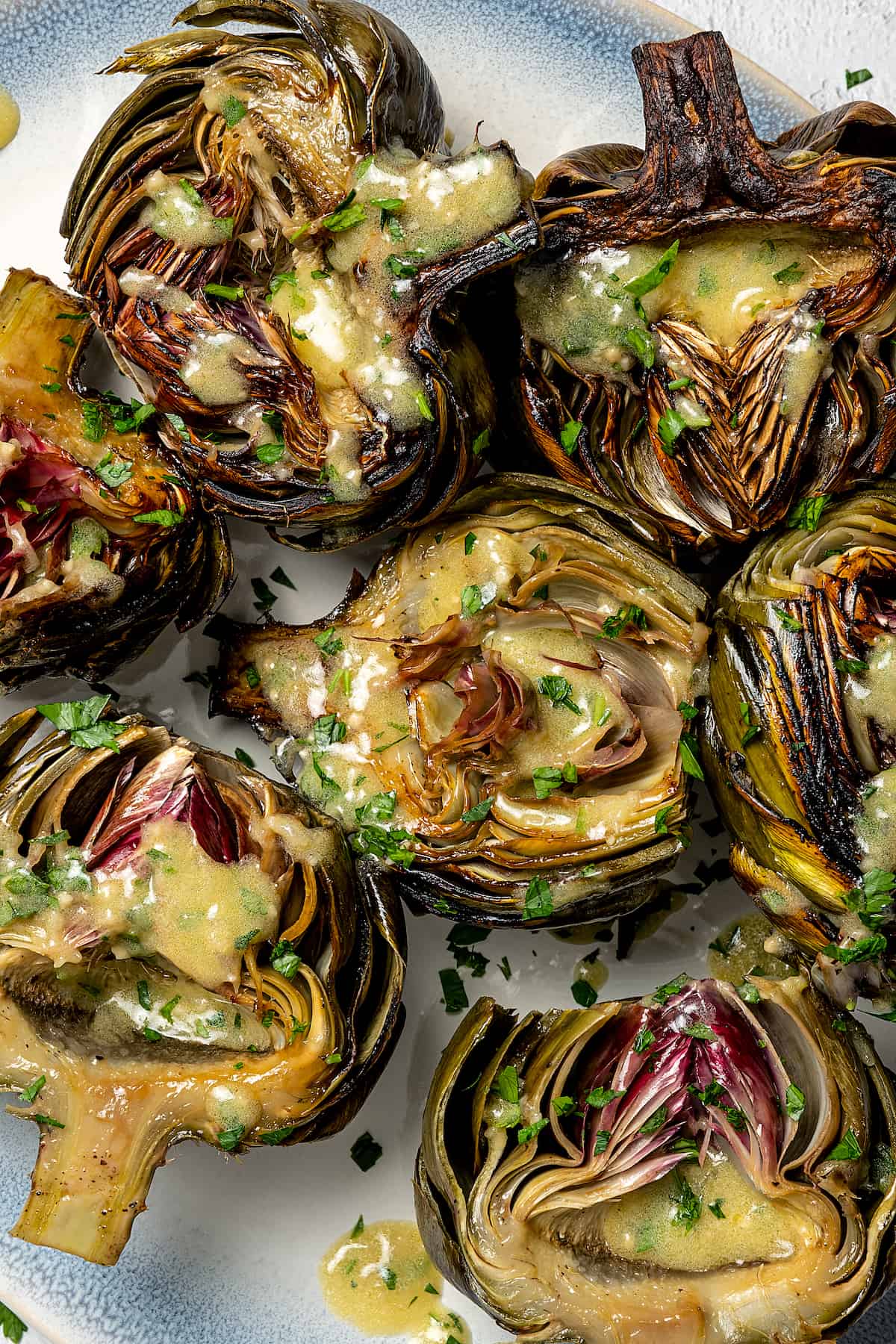 Roasted artichokes, cut side up, drizzled with dressing.