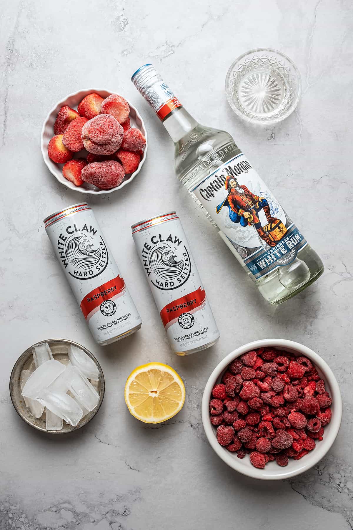 Berries, white claw cans, ice , lemon and Captain Morgan in a bottle.