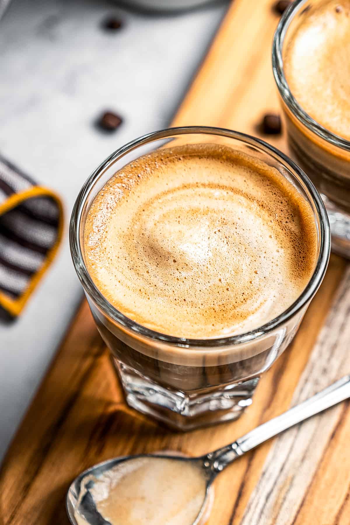 Looking down at 2 glasses with cortado coffee.