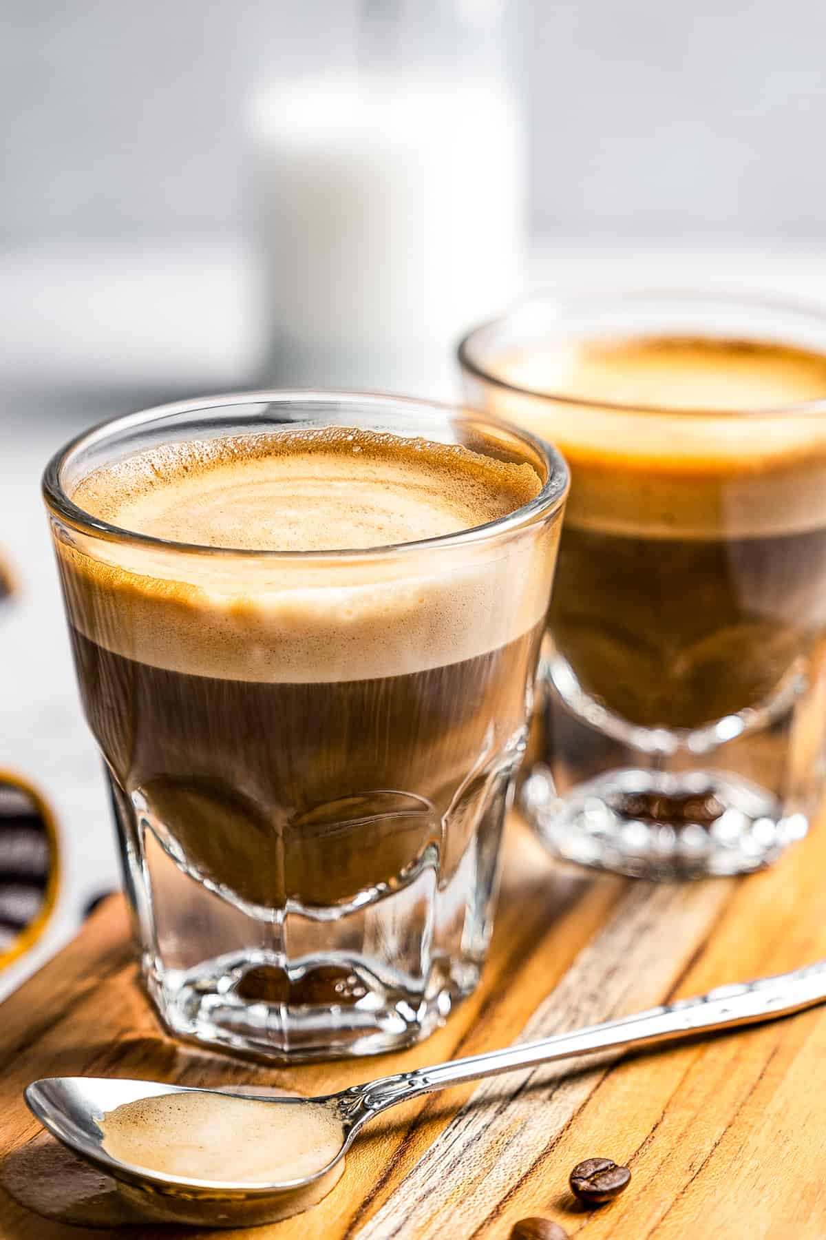 Side shot of two coffee glass mugs filled with cortado coffee.