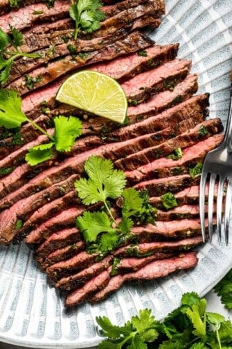 Sliced carne asada on a plate with a serving fork