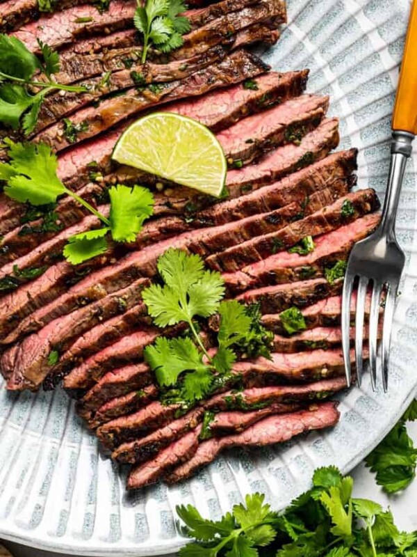 Sliced carne asada on a plate with a serving fork