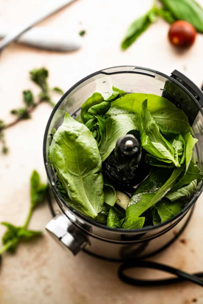 basil leaves in a bowl of a small blender.