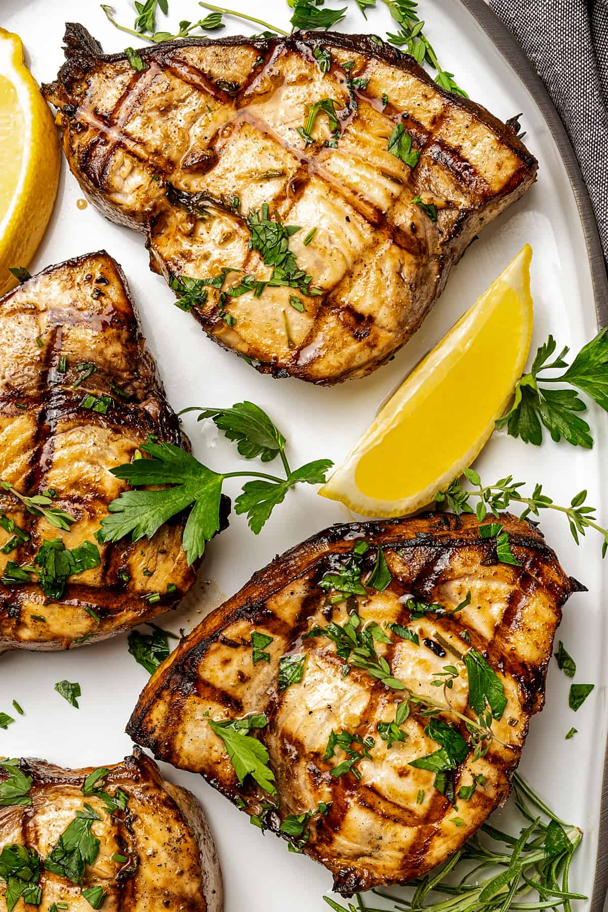up close photo of four grilled swordfish steaks on a serving platter with lemon wedges