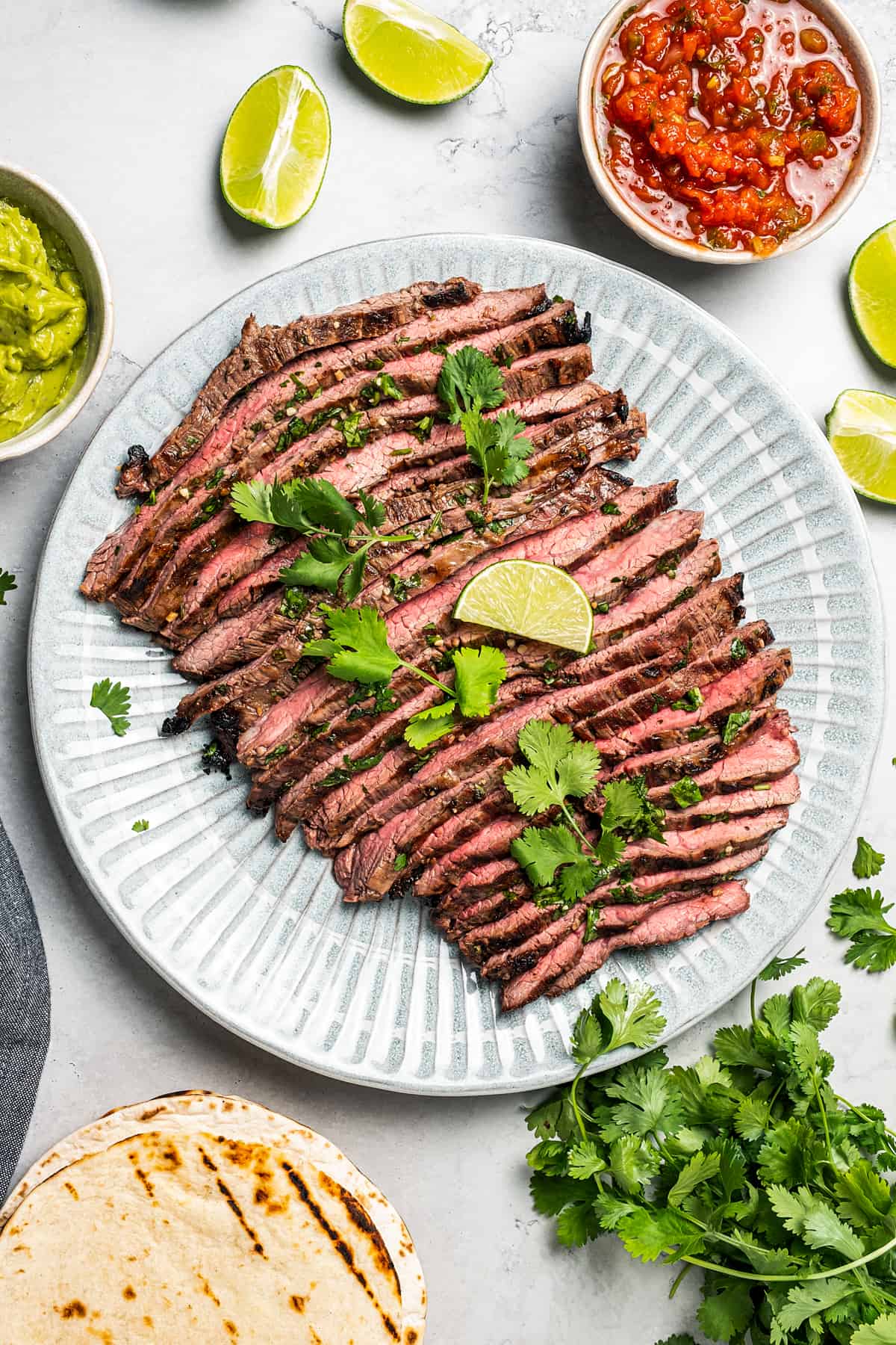 Sliced carne asada on a plate with a serving fork.
