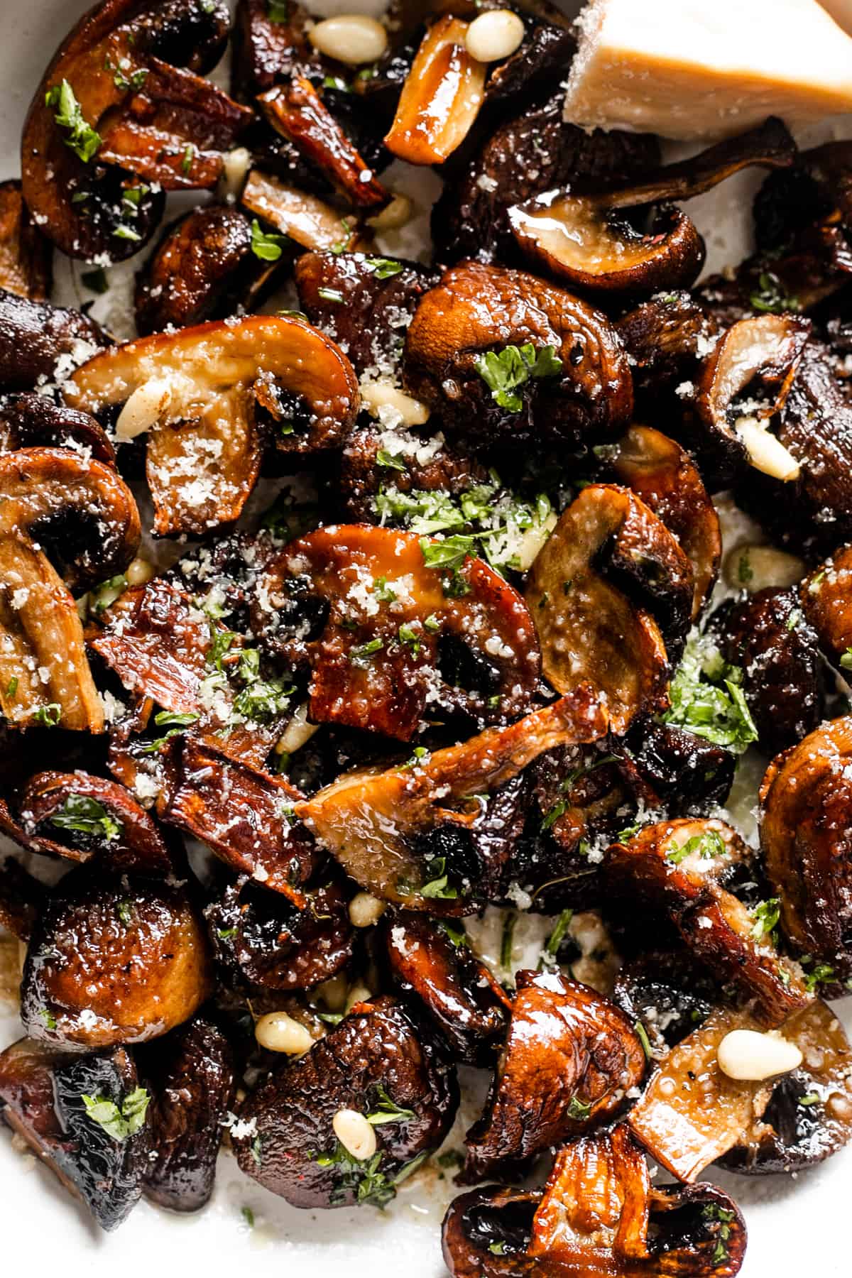 close up shot of bunched up roasted mushrooms topped with grated parmesan cheese.