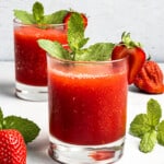 Two glasses filled with red white claw slushies and garnished with strawberry slices