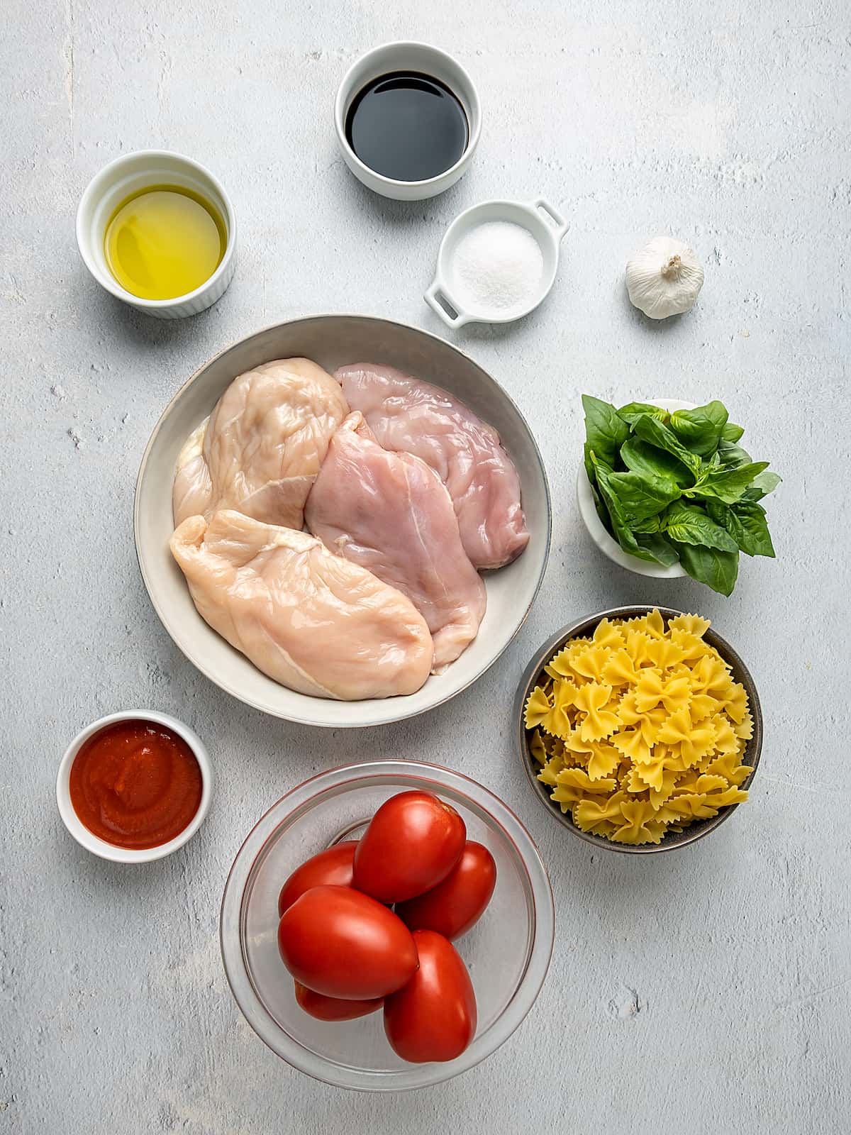 The ingredients for Chicken Bruschetta Pasta laid out in bowls on the counter.