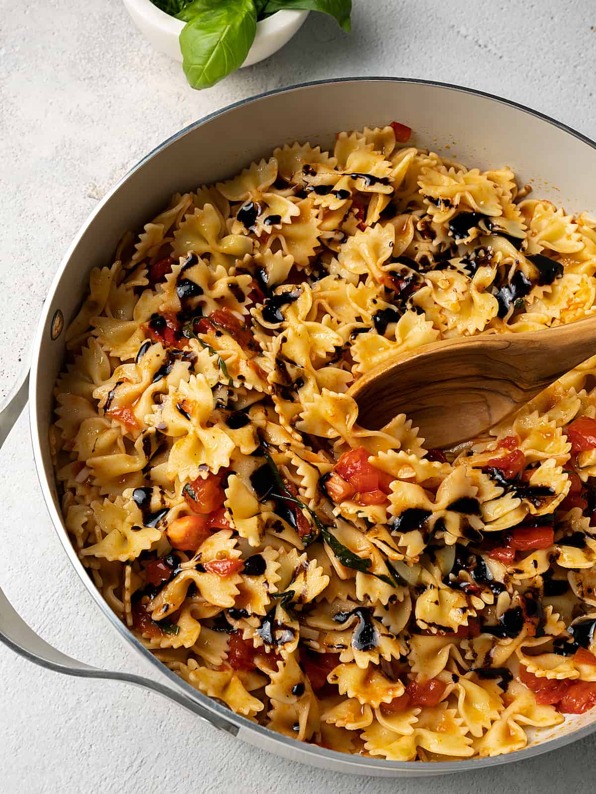 Balsamic vinaigrette being stirred into pasta with bruschetta sauce.