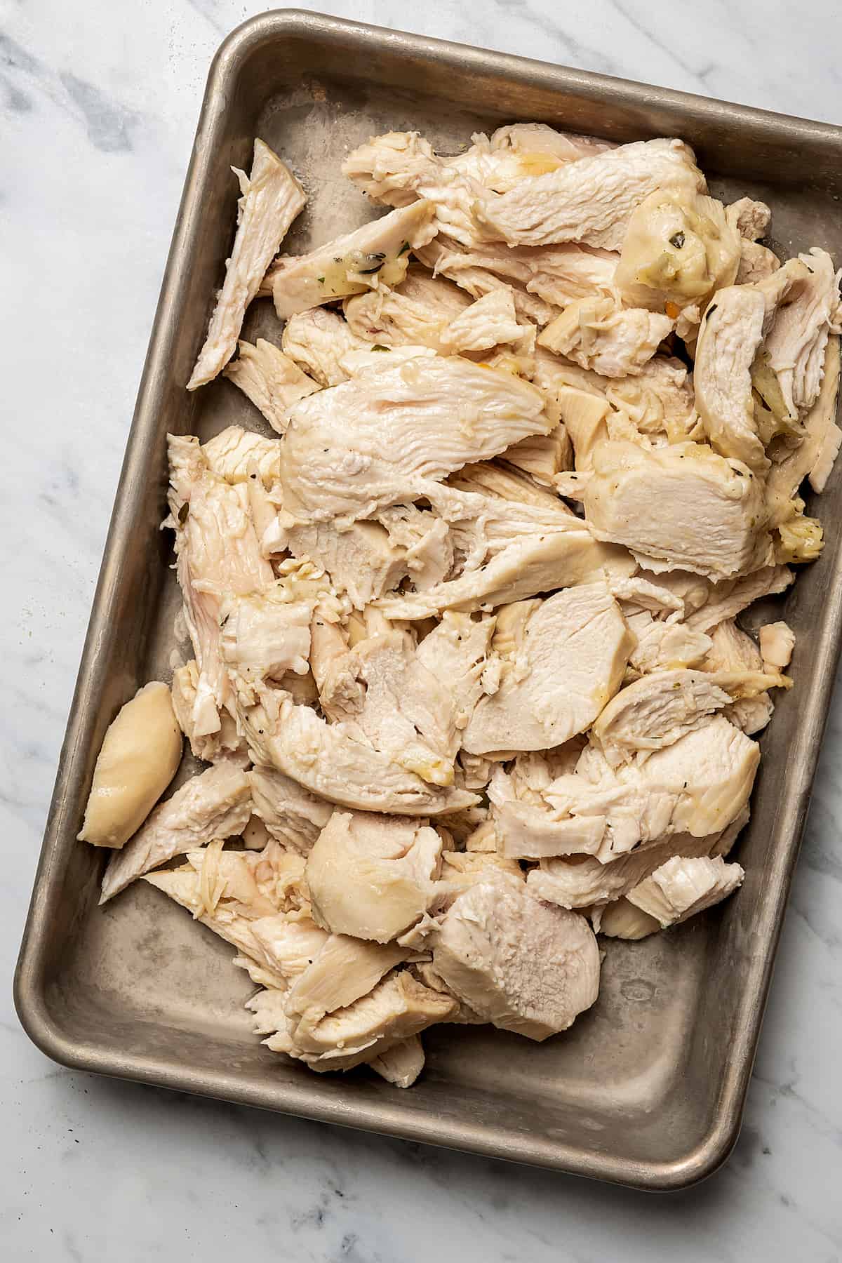 Cut-up, cooked chicken on a tray.
