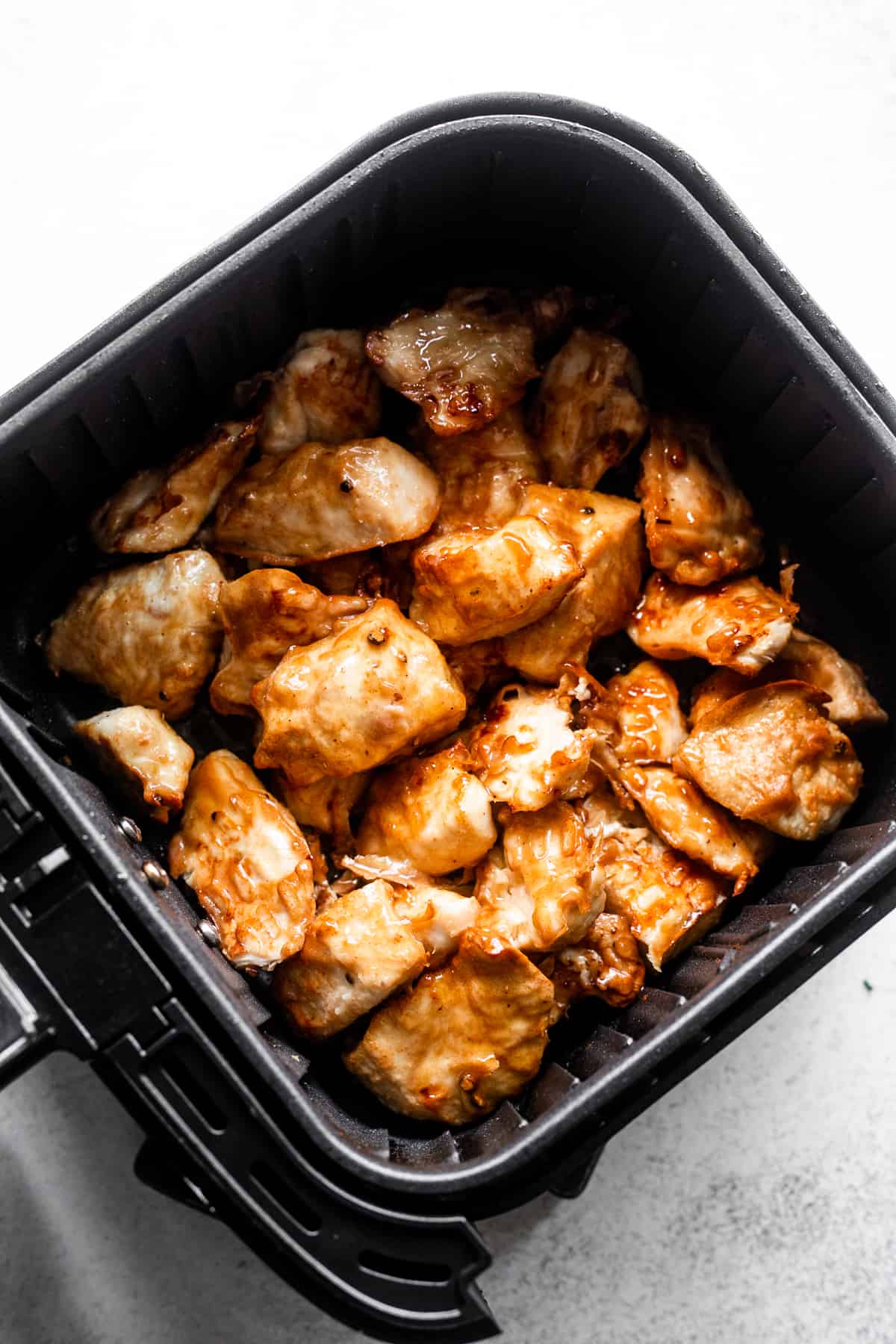 cooking chicken nuggets in a black air fryer basket.