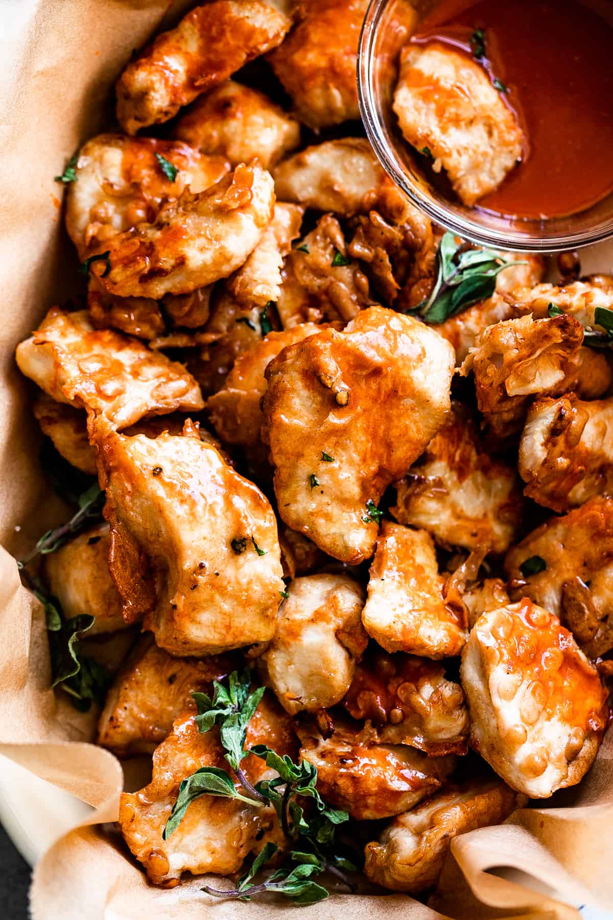 up close shot of air fryer buffalo chicken bites served in a basket with side bowl of buffalo sauce.