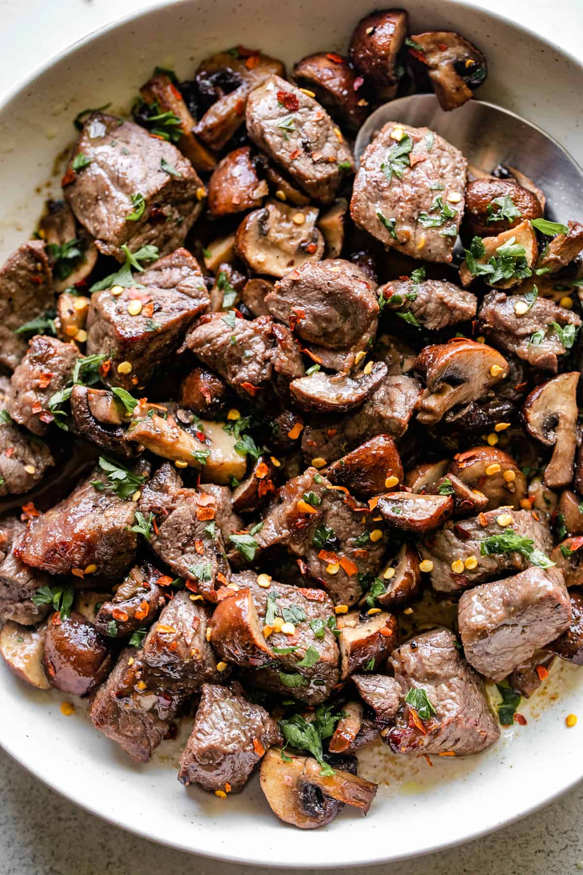 air fryer steak bites and mushrooms served in a round white serving platter.