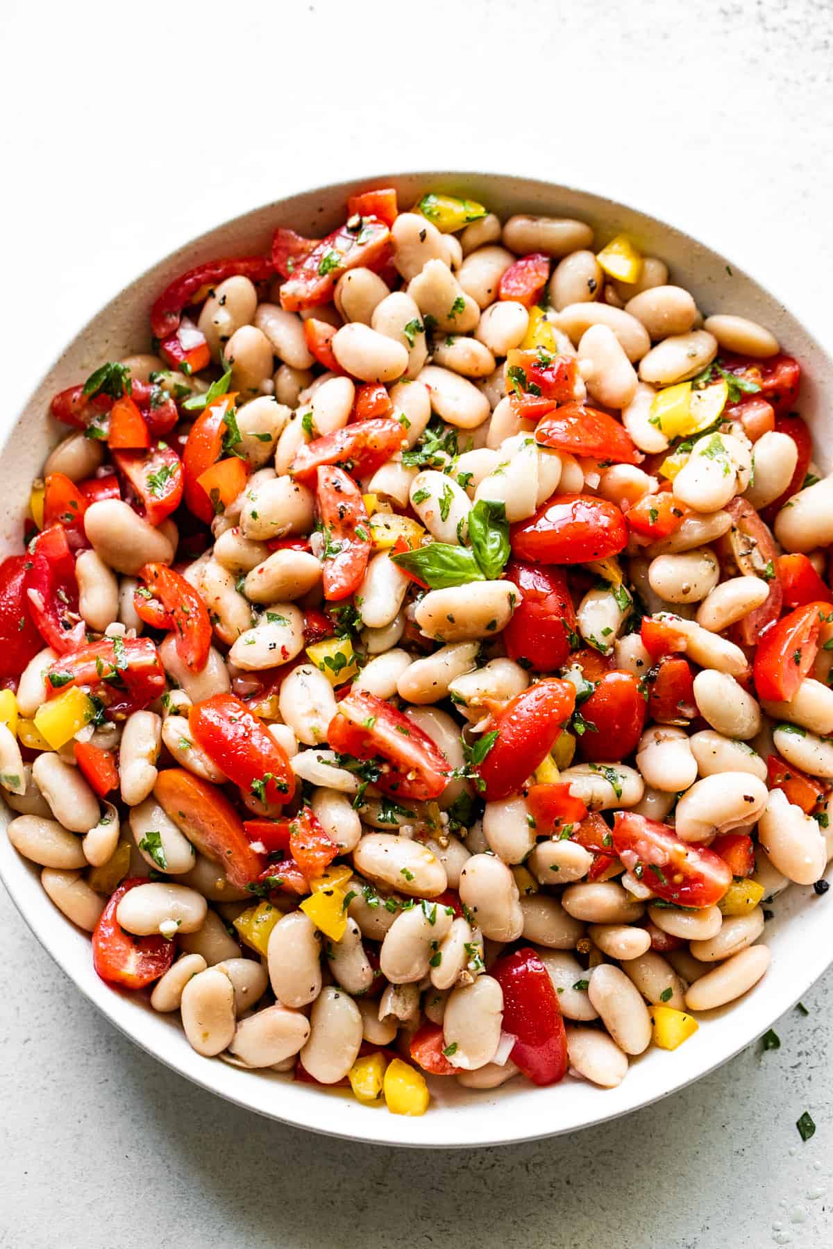 overhead shot of a salad bowl with cannellini beans, tomatoes, and bell peppers.