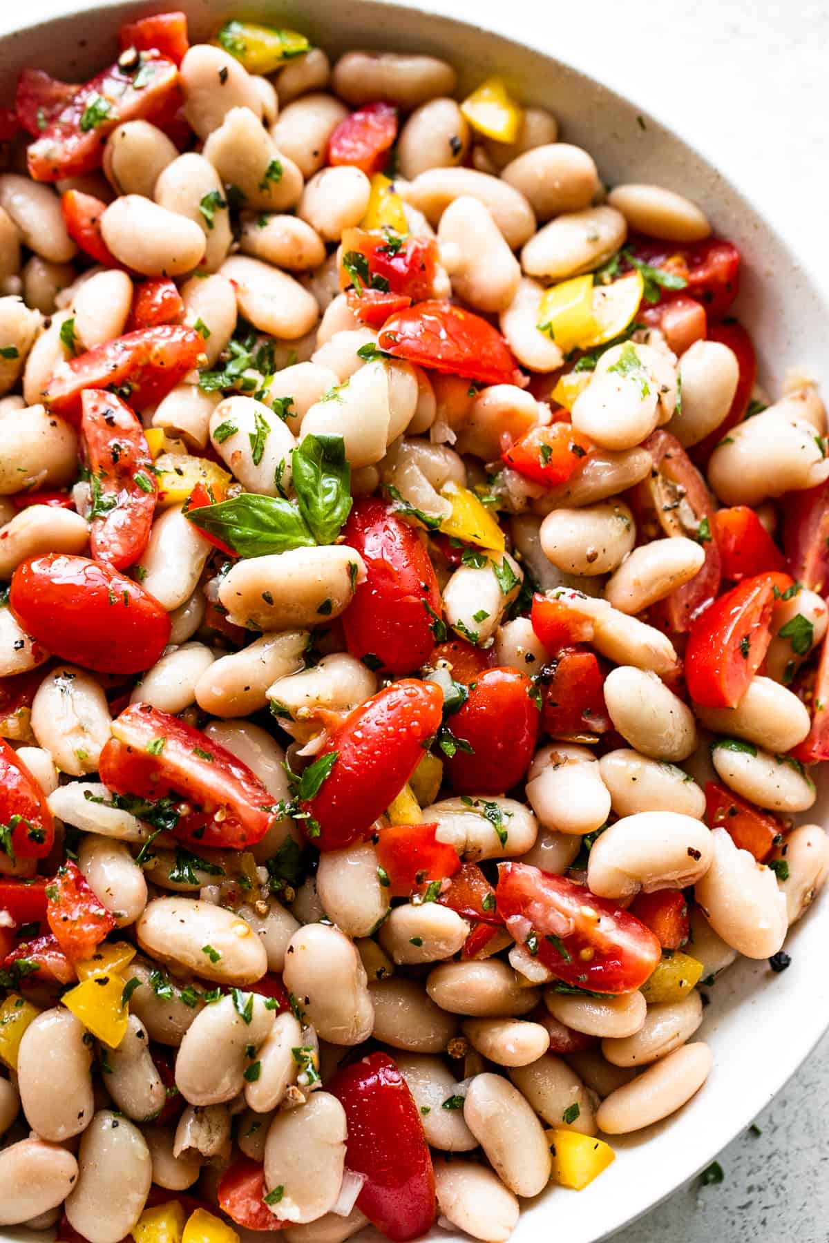 overhead shot of a salad bowl with cannellini beans, chopped tomatoes, and bell peppers.