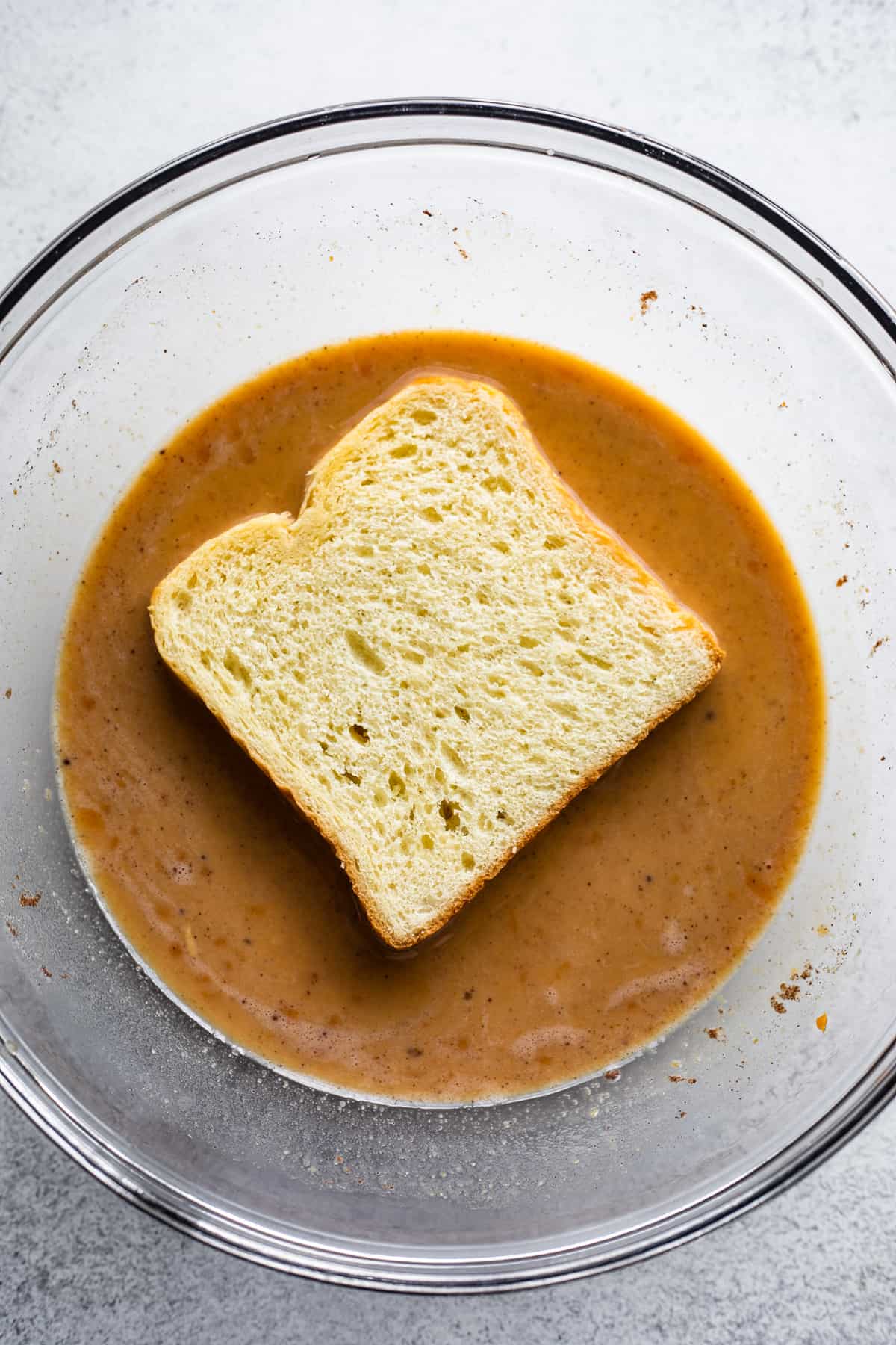 soaking a slice of bread in a mixture of pumpkin puree, milk, and eggs.