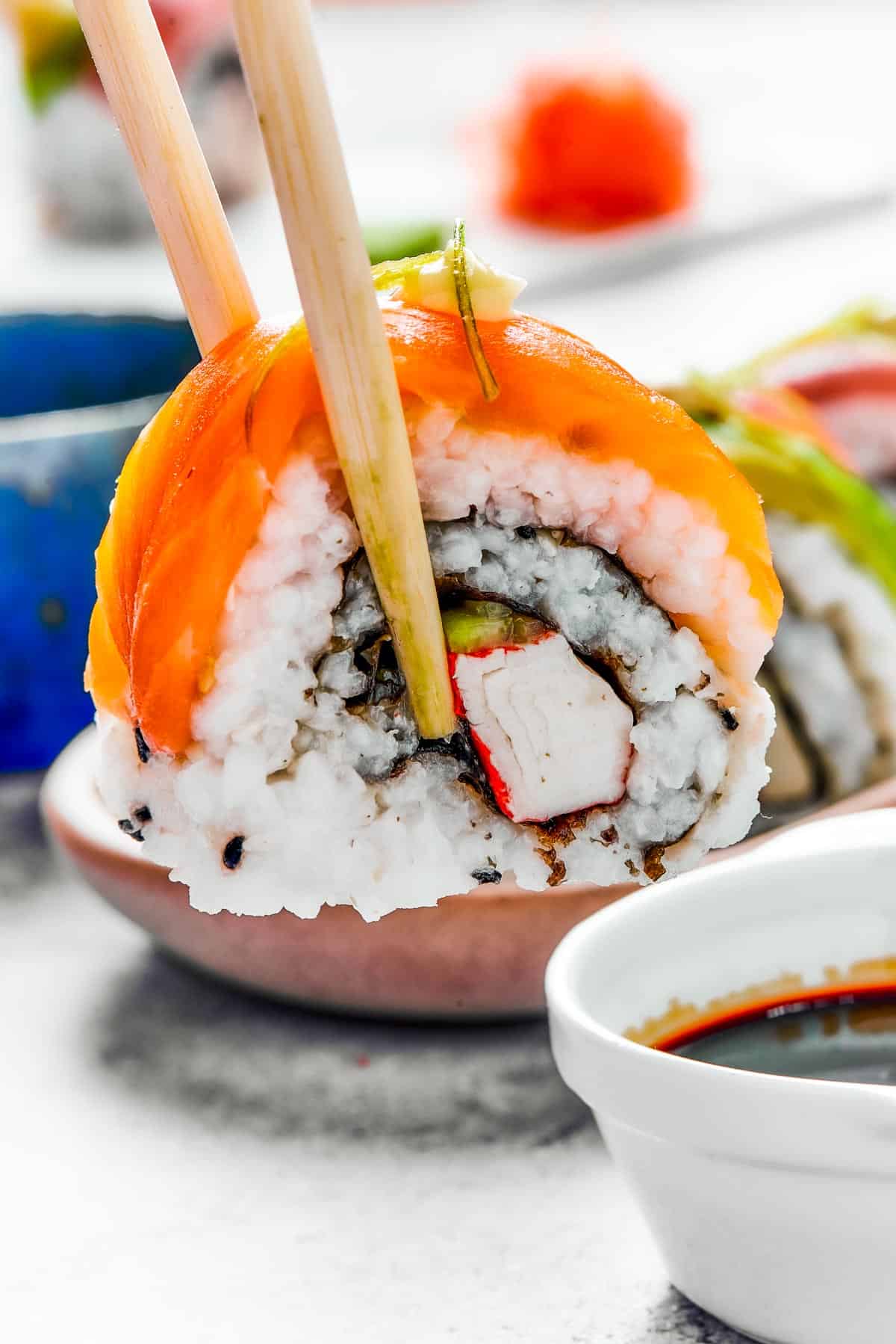 Rainbow roll sushi in between chopsticks.