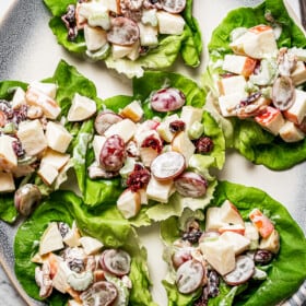 Overhead shot of a platter of Bibb lettuce leaves with servings of creamy fruit salad on each one.