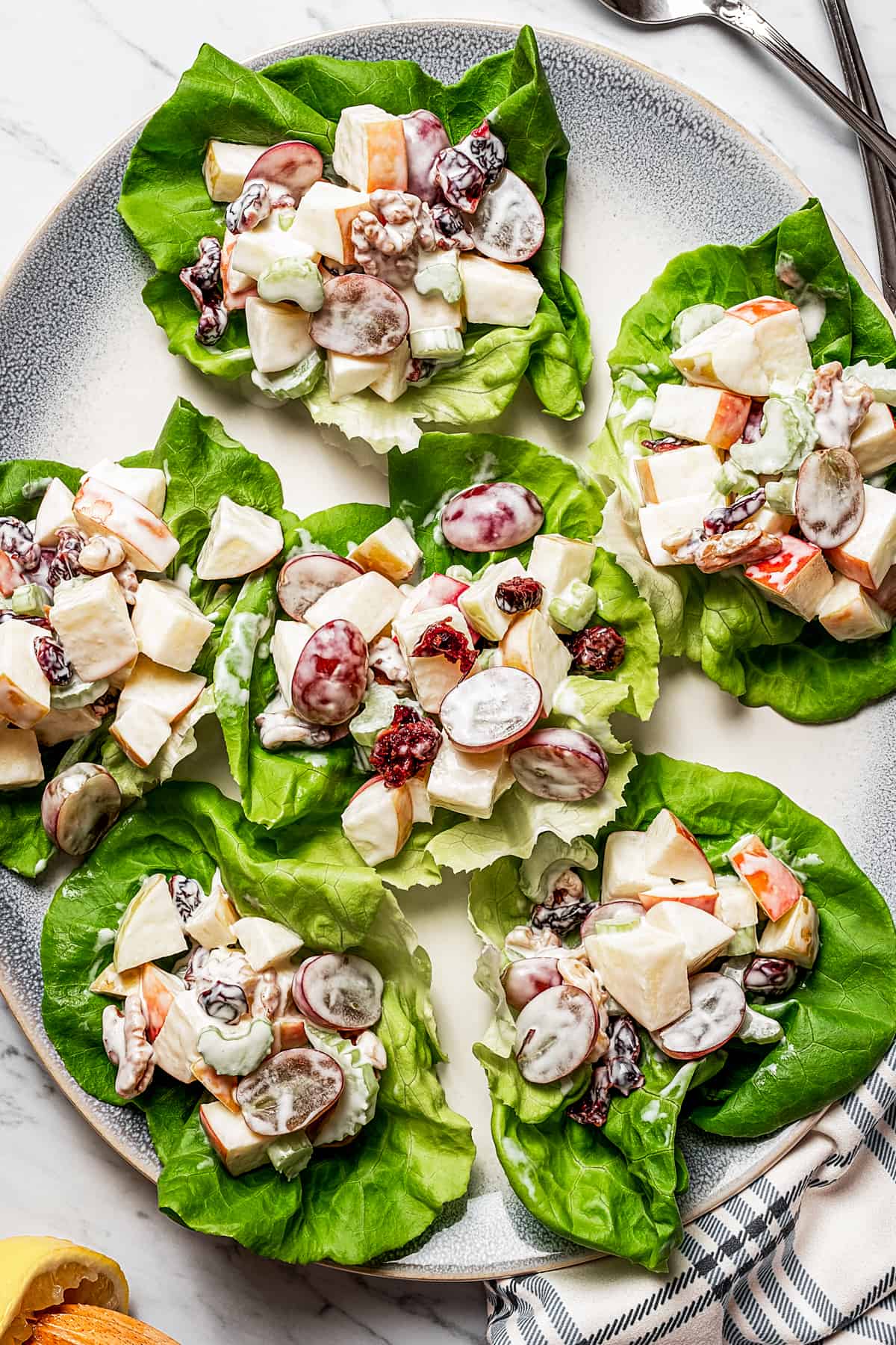 Overhead shot of a platter of Bibb lettuce leaves with servings of creamy fruit salad on each one.