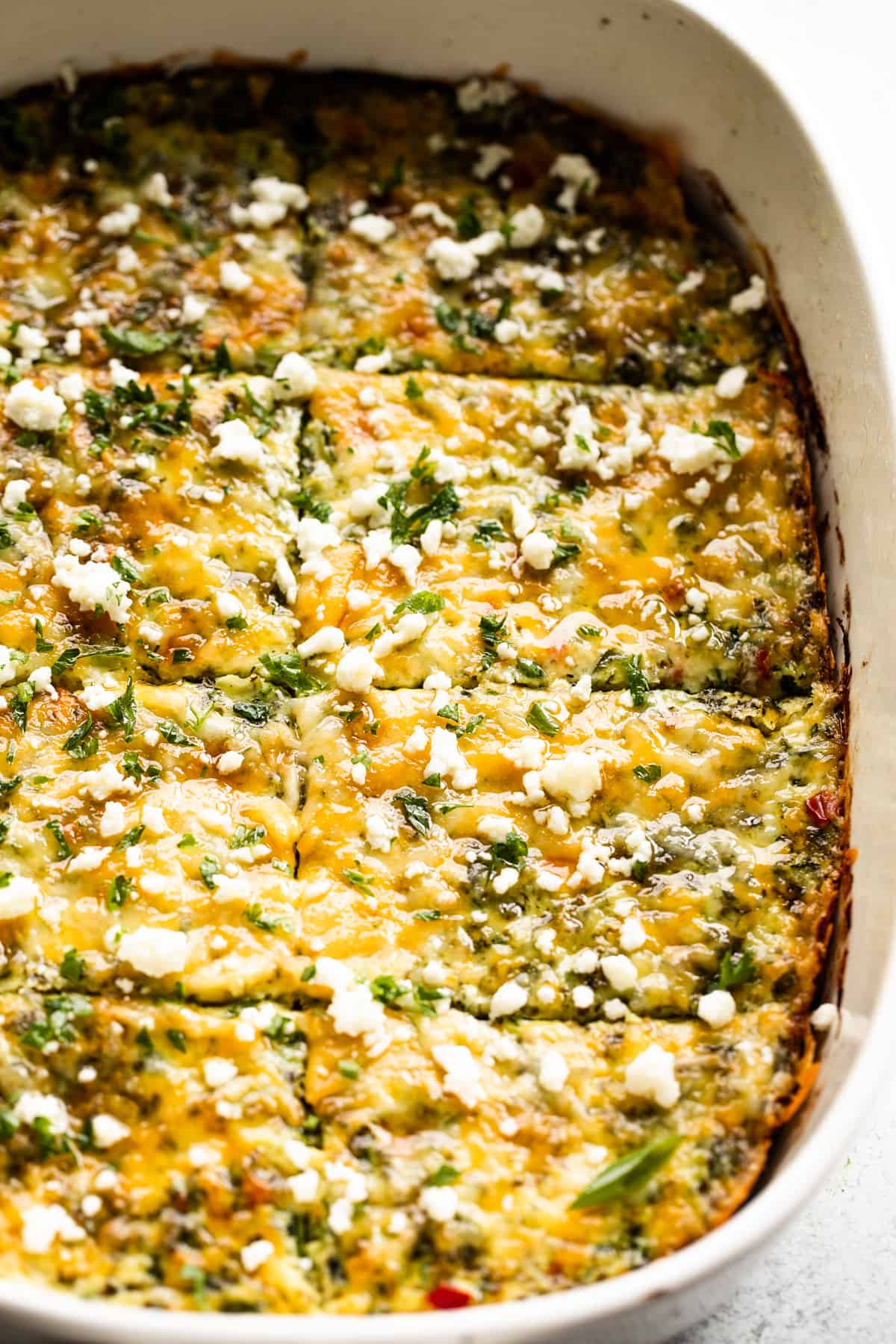 overhead shot of a white baking dish with zucchini egg bake cut into squares.