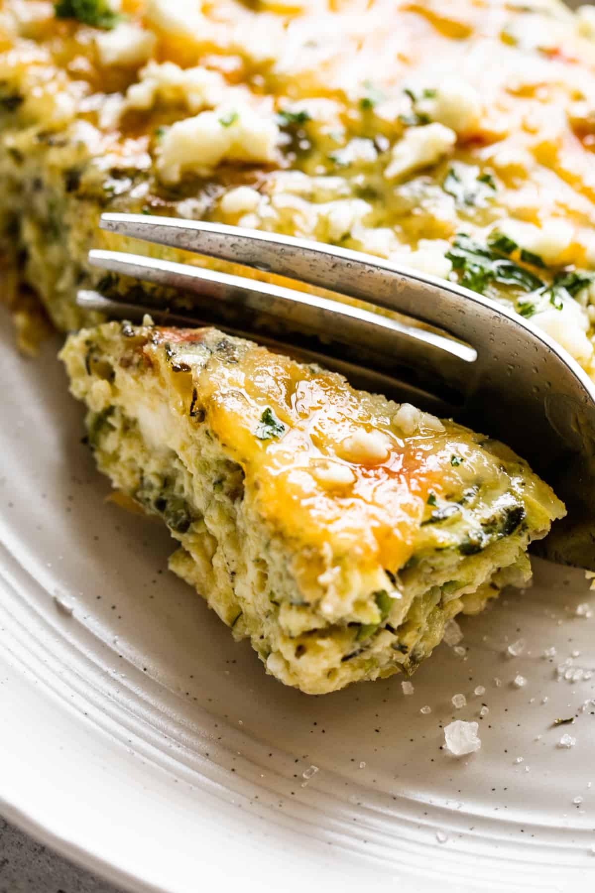 a fork cutting into the corner of a zucchini egg bake square.