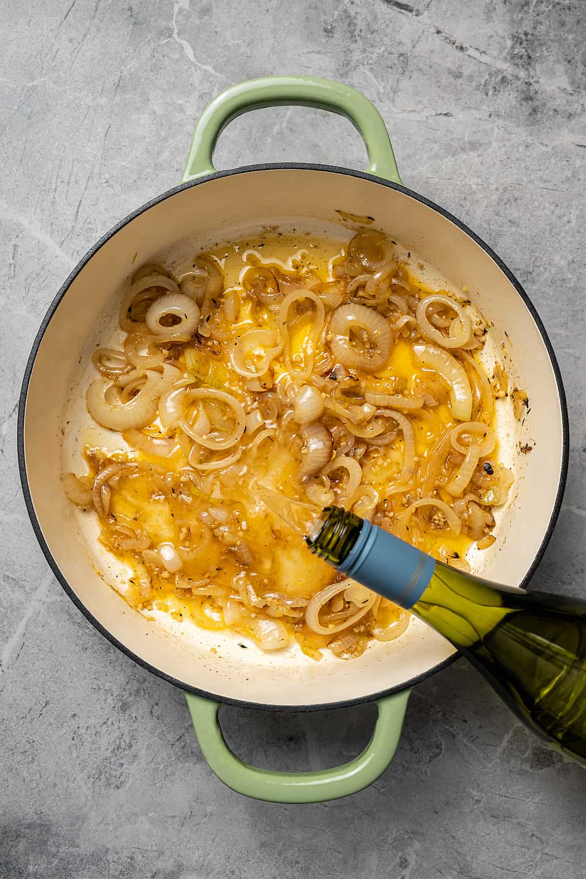Adding wine to a pan of onions.