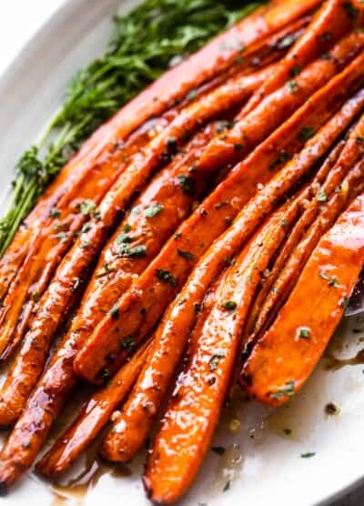 close up shot of air fryer cooked carrots arranged on a long oval platter and drizzled with balsamic glaze.