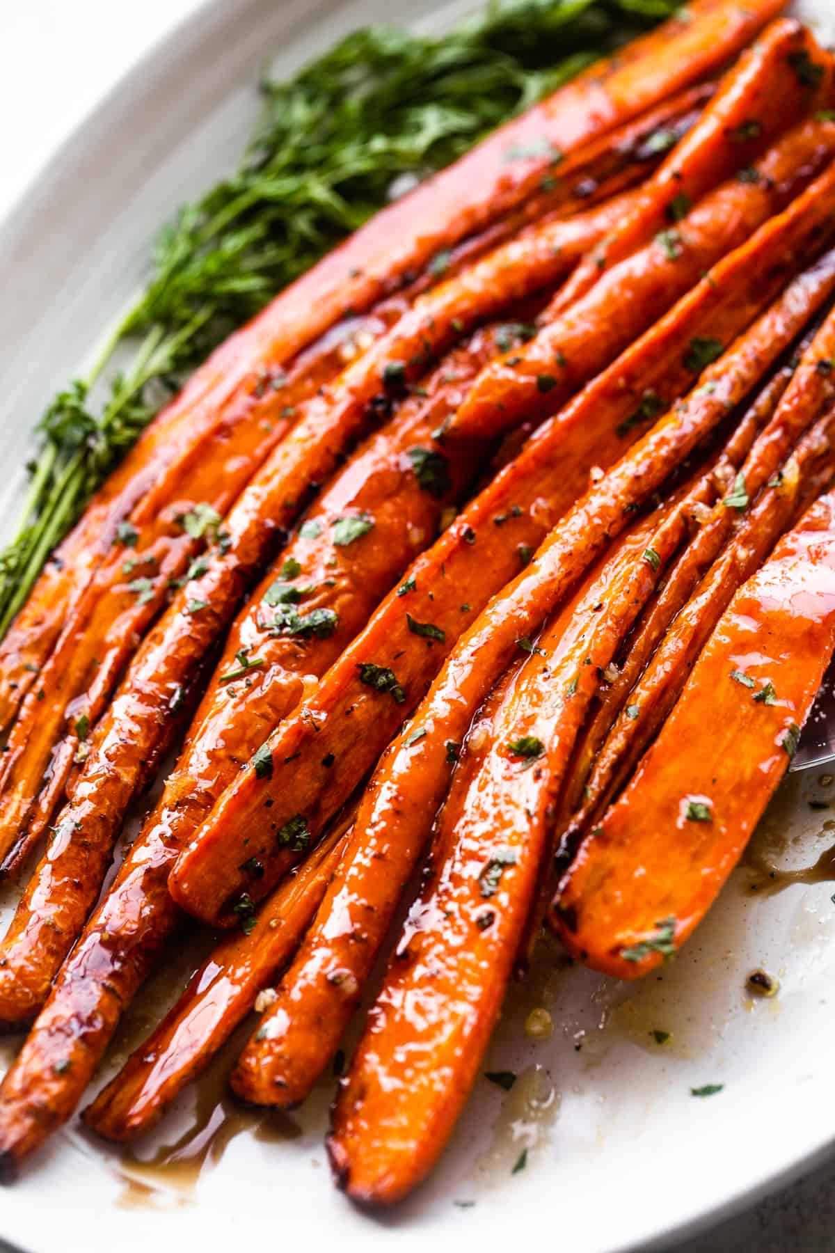 close up shot of air fryer cooked carrots arranged on a long oblong platter and drizzled with balsamic glaze.