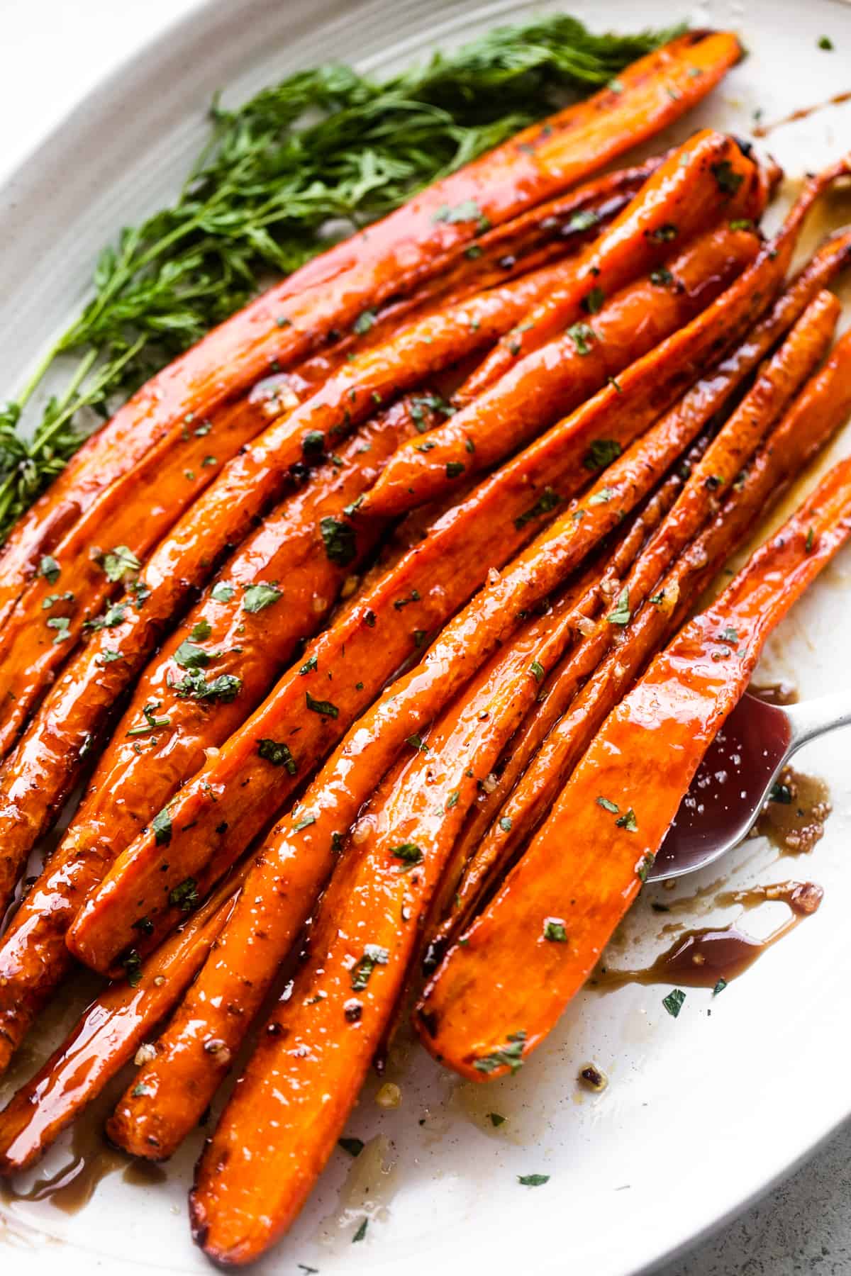 close up side shot of air fryer cooked carrots arranged on a long oblong platter and drizzled with balsamic glaze.
