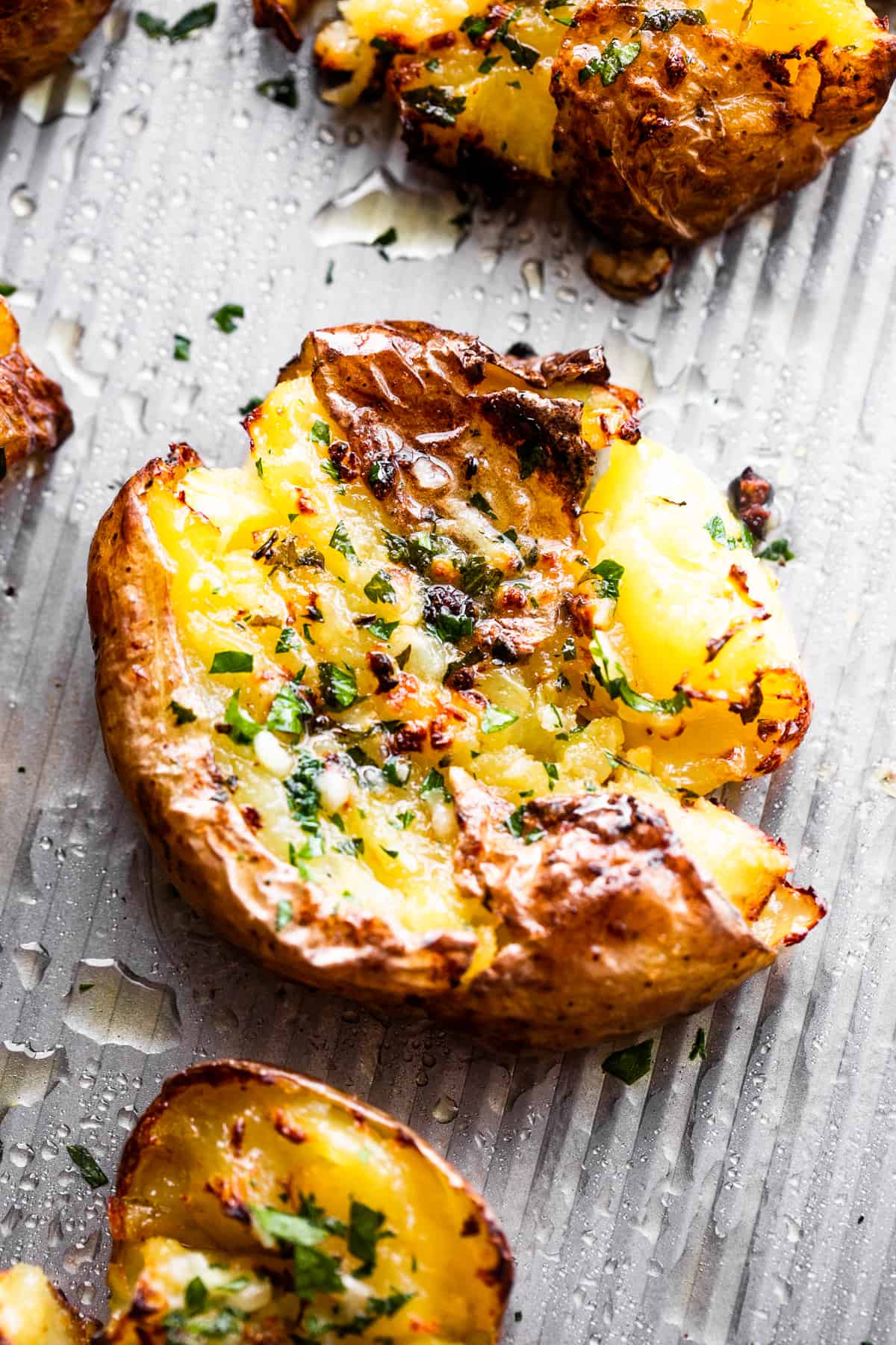 close up shot of smashed potatoes topped with chopped parsley