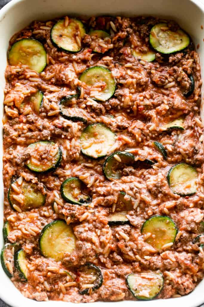 ground beef and slices of zucchini arranged in a baking dish to make Beef Zucchini Casserole.