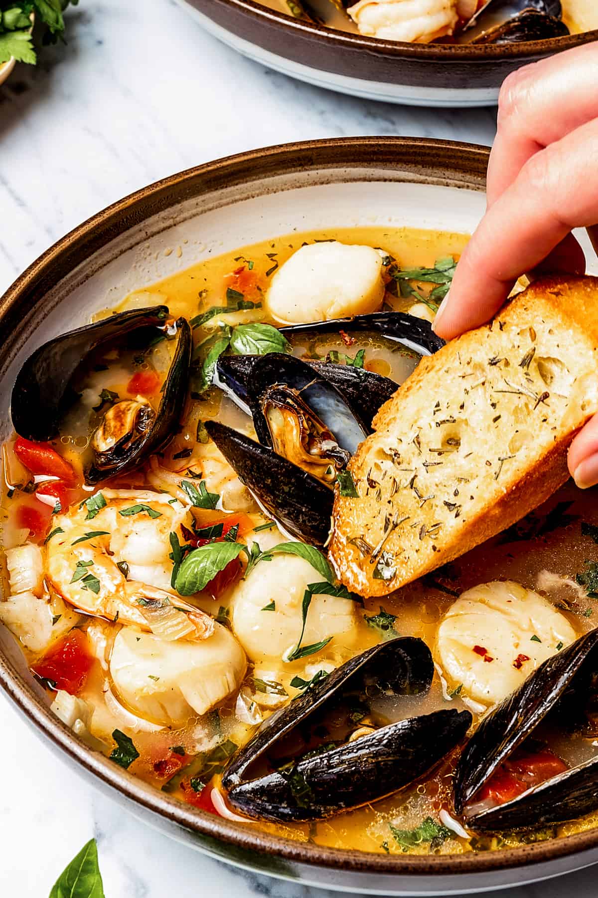 Dipping a baguette slice into bouillabaisse.