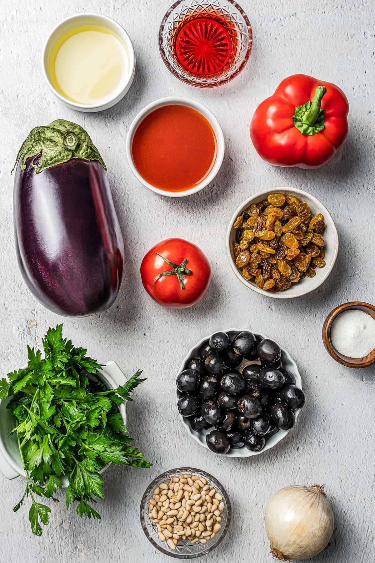 From top left: Olive oil, red wine vinegar, red bell pepper, eggplant, tomato sauce, fresh tomato, golden raisins, fresh parsley, black olives, salt, pine nuts, onion.