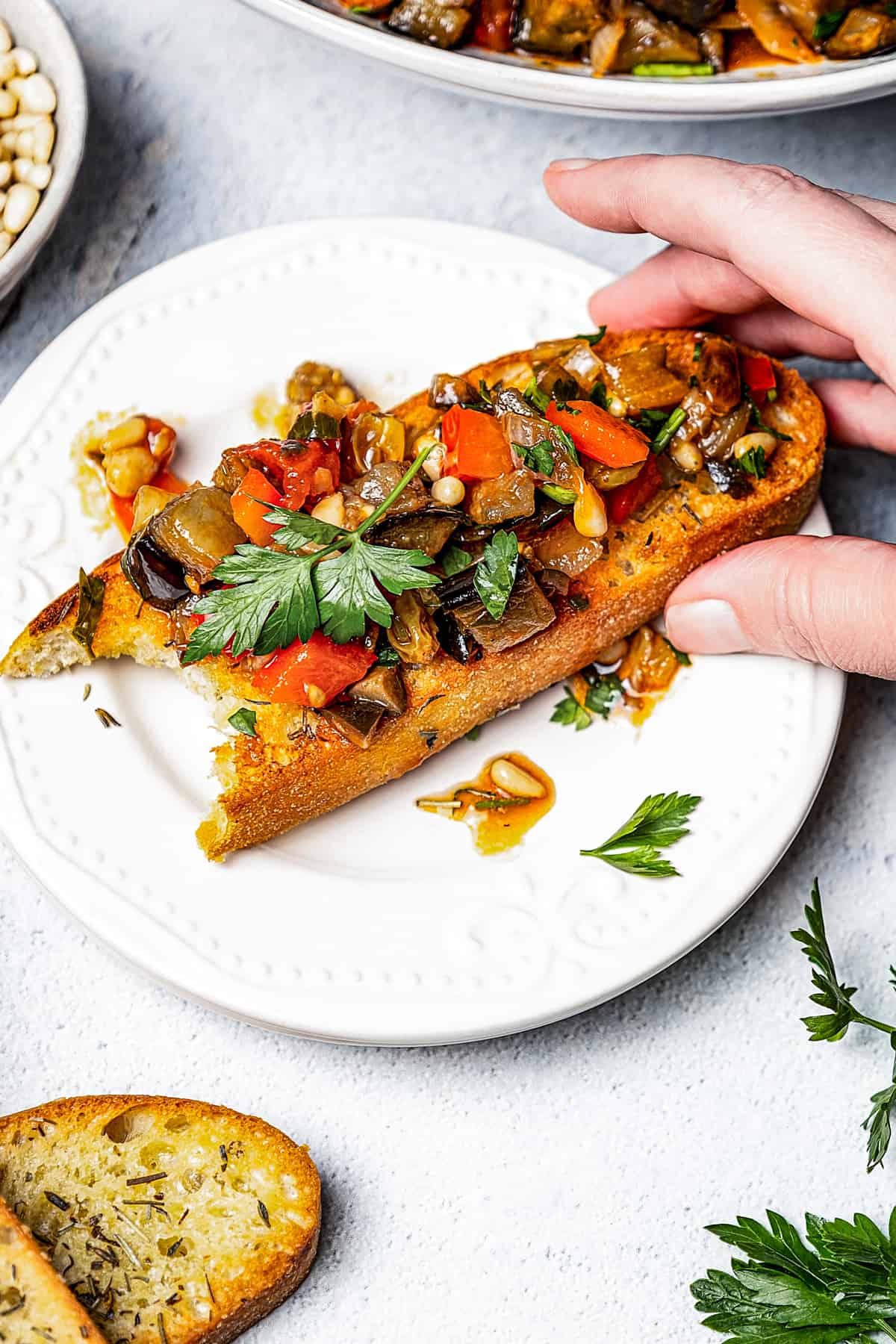 A slice of toasted bread topped with eggplant relish. One bite has been taken from the end of the toast.