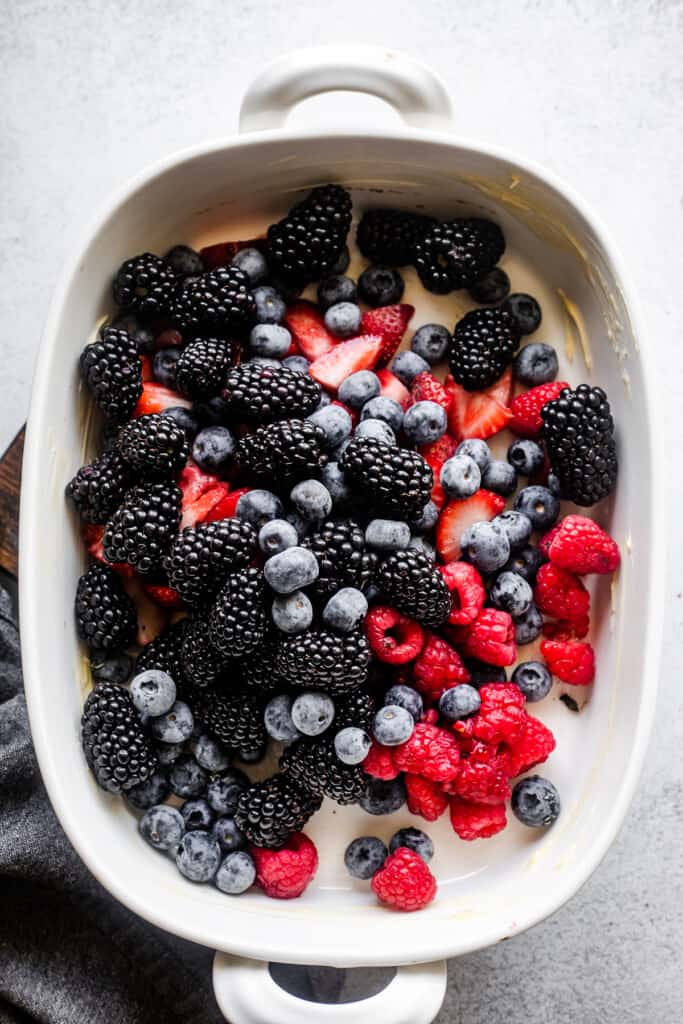 white baking dish filled with raspberries, strawberries, blackberries, and blueberries.