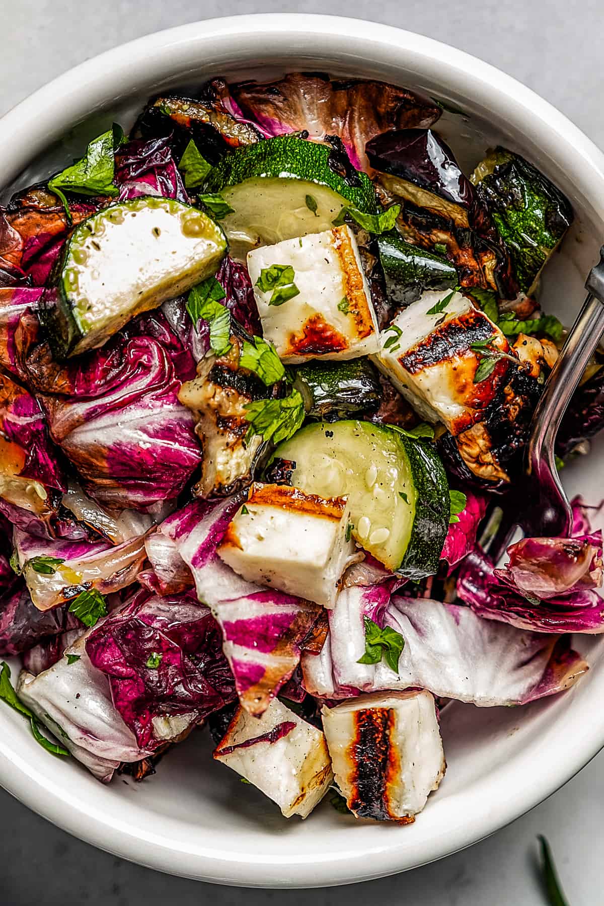Cut grilled vegetable salad in a small bowl with a fork.