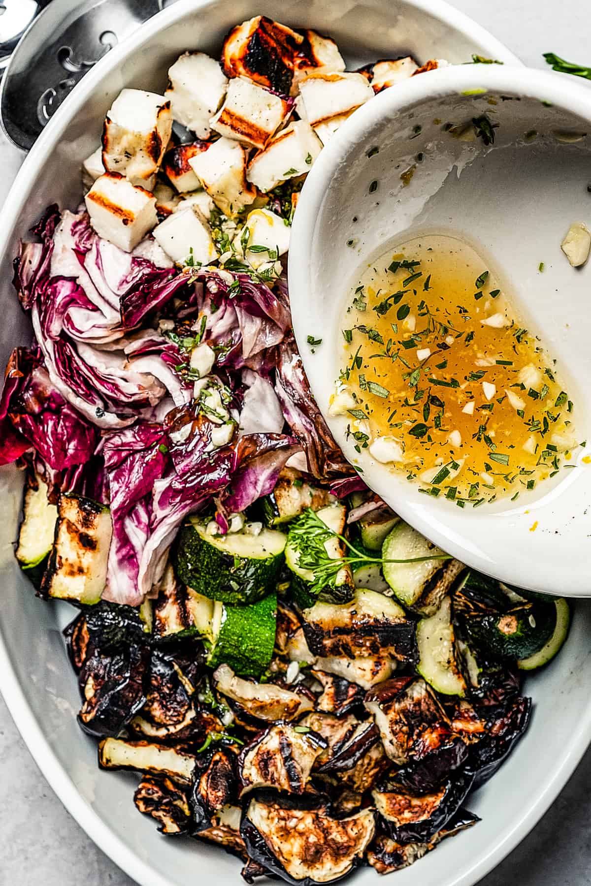 Salad dressing being poured over a grilled salad.