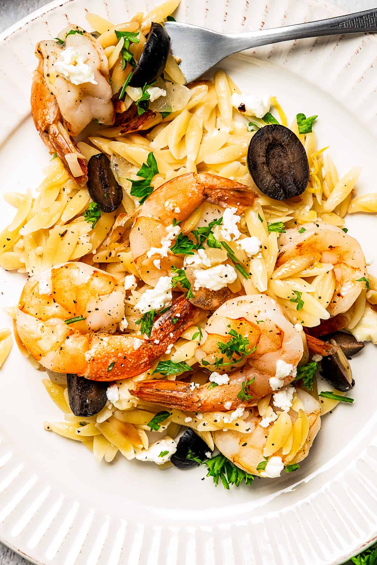 white plate with a serving of one-pot shrimp and orzo pasta with a fork.