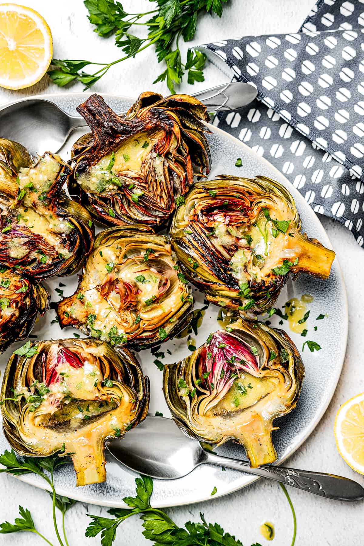 A platter of cooked artichoke halves, drizzled with dressing.