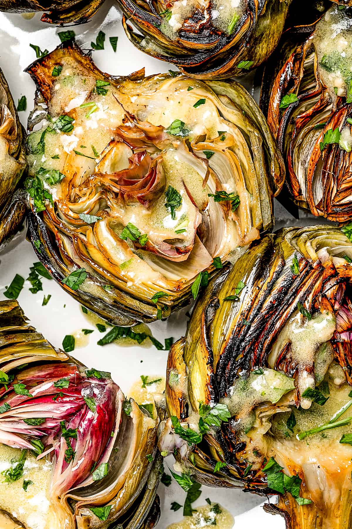 close up shot of roasted artichokes, cut side up, drizzled with dressing.