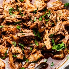 Pulled pork garnished with julienned herbs.