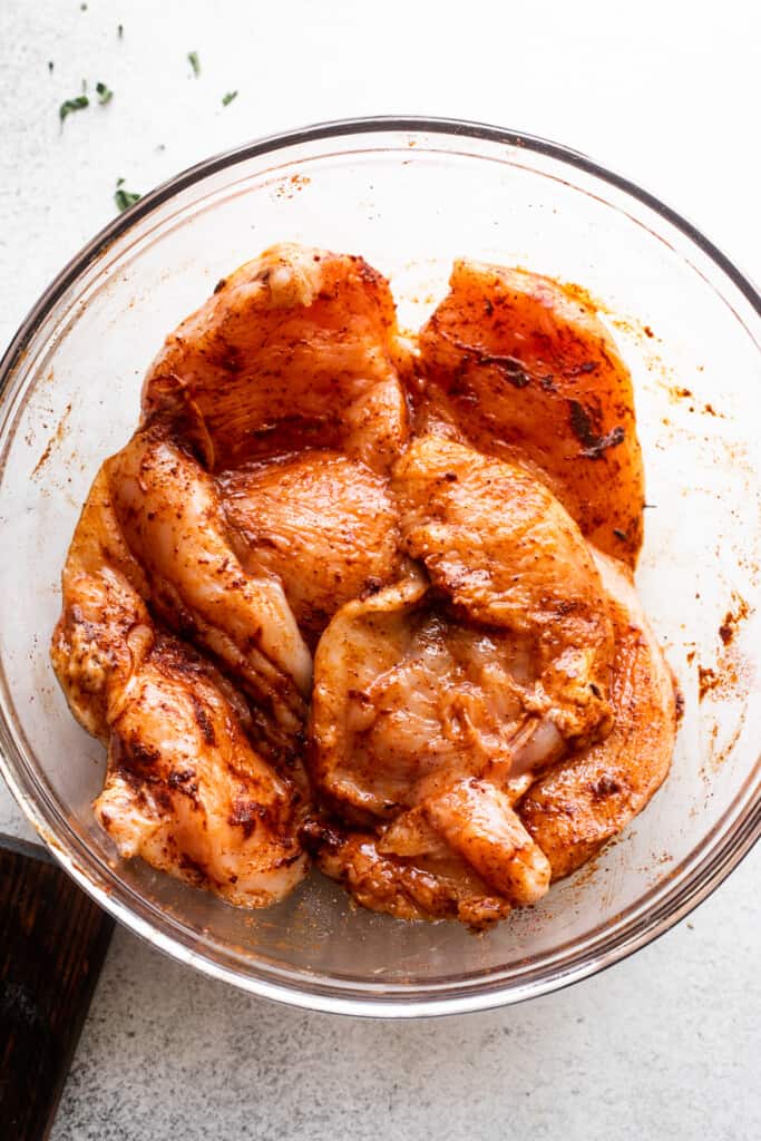 cajun-seasoned chicken breasts in a large glass bowl.