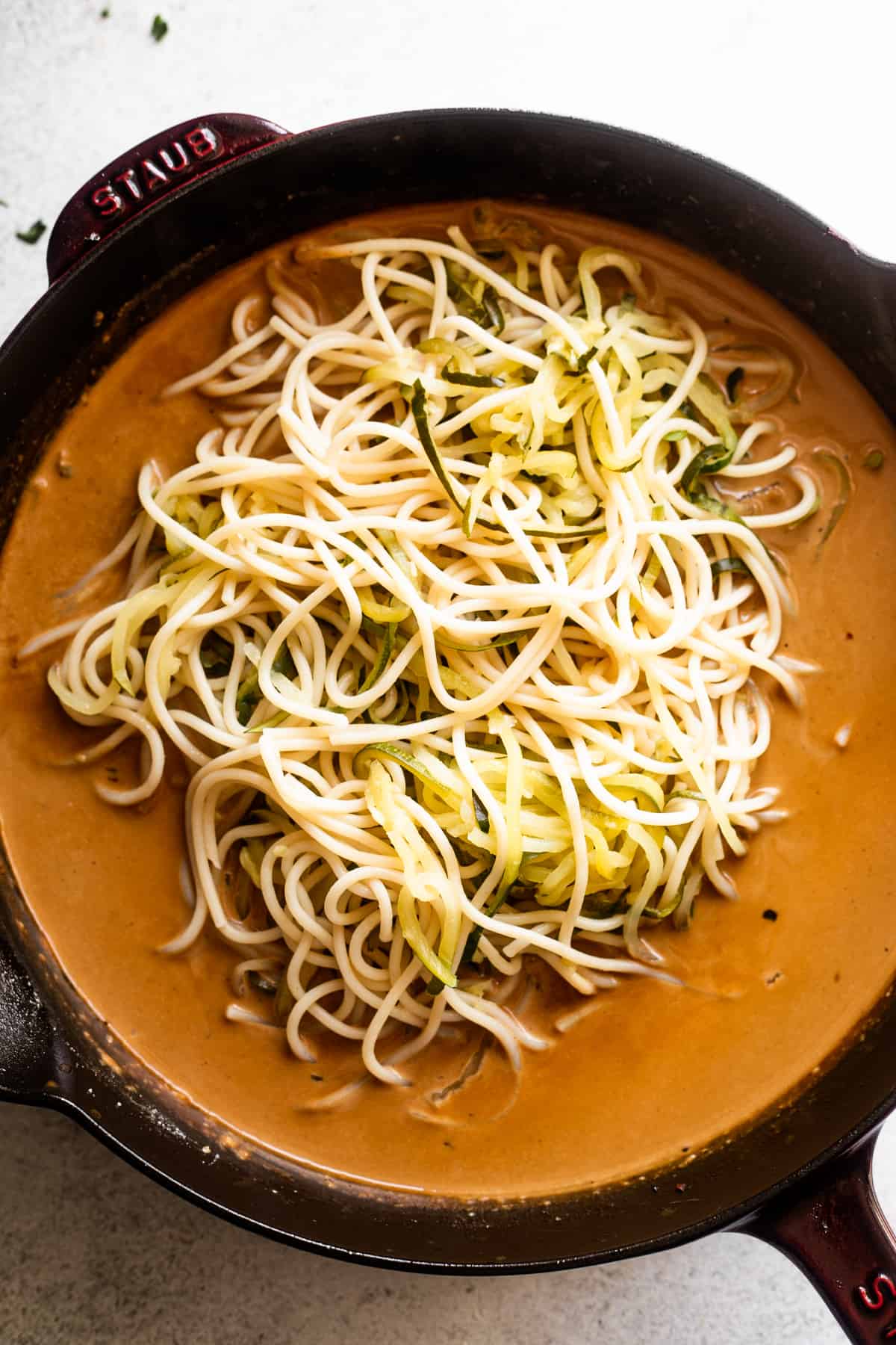 overhead shot of homemade cream sauce in a cast iron skillet with zucchini noodles placed in the center of the sauce.