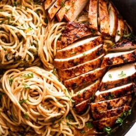 overhead shot of a cast iron skillet with two nests of zoodles arranged on the left side, and sliced chicken breasts arranged on the right side of the skillet.